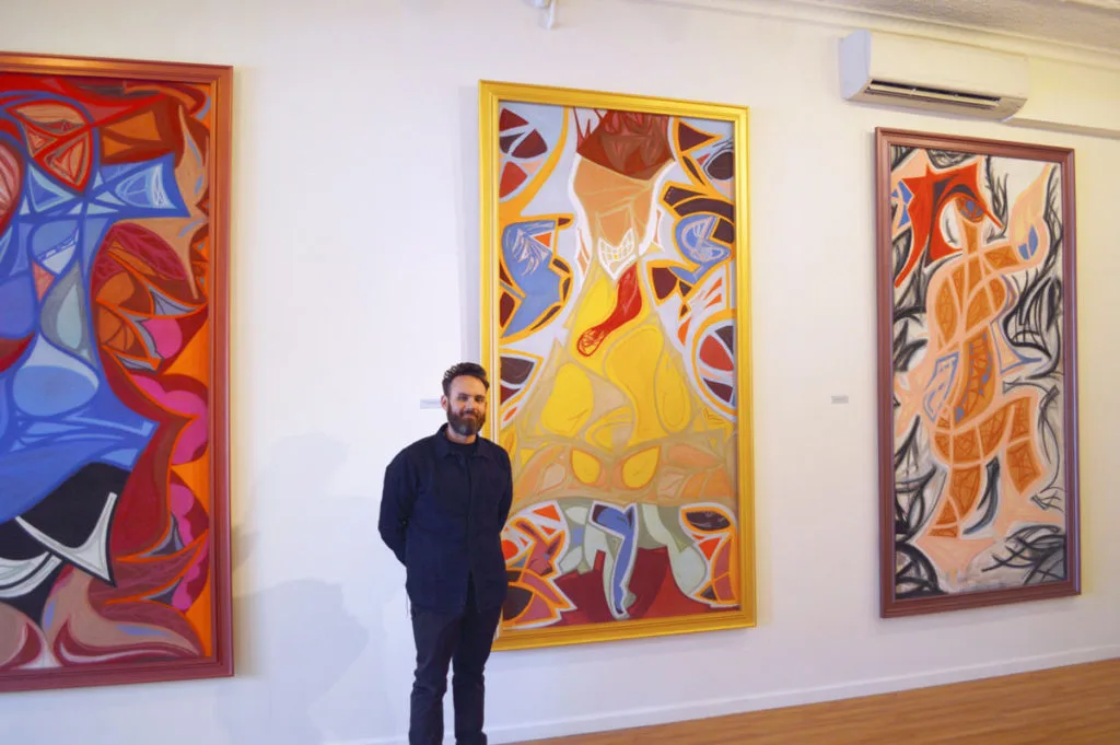 Ian James Roche with paintings in gallery